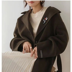 Elegant purple tulip brooch with crystals pinned on a brown wool coat collar