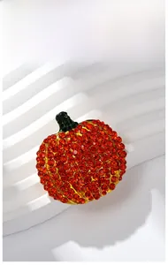 Detailaufnahme einer goldfarbenen Kürbis-Brosche mit orangen und grünen Strasssteinen