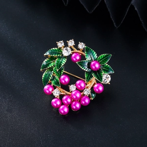 Détail de la broche fleur avec feuilles d'émail vert, perles rouges et cristaux sur noir