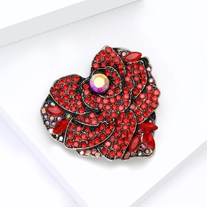 Detailed close-up of heart-shaped rose brooch with red rhinestones and vintage metal finish