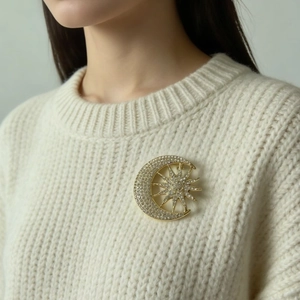 Elegant gold celestial sun and moon brooch with full diamonds on a beige knitted sweater