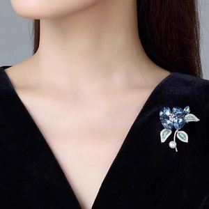 Broche orchidée en cristal bleu avec feuilles vertes et perle sur un costume noir chic