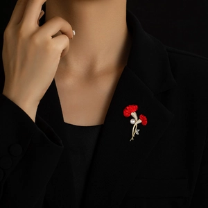 Elegante rote Nelken-Brosche mit Perlen und Goldstiel an einem schwarzen Blazer