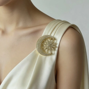 Elegant gold celestial brooch with rhinestones on a white silk dress, star and moon design