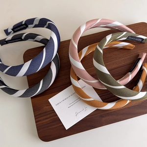 Set of padded striped fabric headbands in assorted colors on a wooden display board