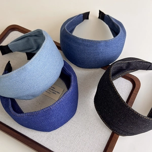 Chic denim padded headbands in four shades with yellow contrast stitching on wooden tray
