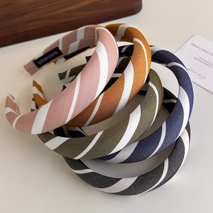 Close-up of assorted striped sponge headbands with handmade woven labels in a neat stack