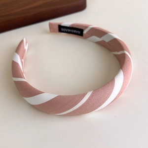 Detail of pink and white striped fabric headband featuring a woven handmade label