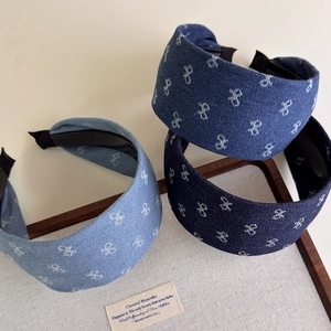 Detailed macro view of denim headbands with white embroidery on a wooden display