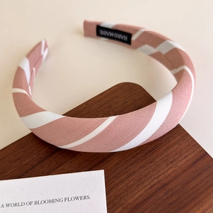 Detail of pink and white striped padded headband with handmade label on wooden tray