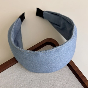 Detailed close-up of blue denim headband with yellow topstitching on wooden background
