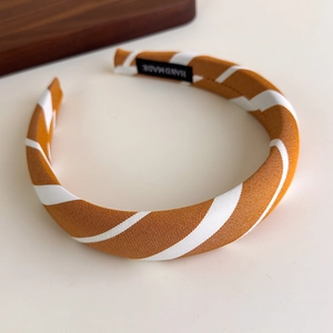 Close-up of orange and white striped fabric headband with handmade tag detail