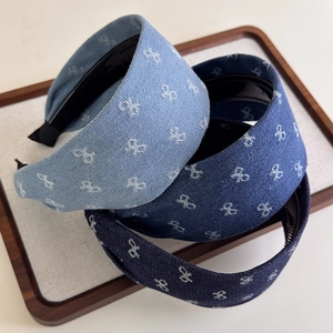 Detail view of denim headbands with white bow embroidery in light to dark blue shades