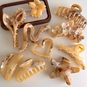 Amber marble plastic claw hair clip set in heart, flower and star shapes on white backdrop