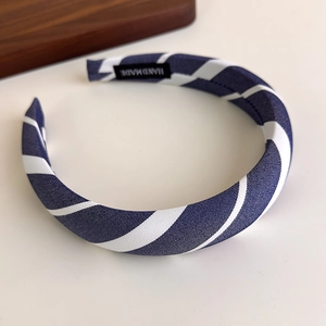 Detail showing deep blue and white striped fabric headband with a handmade inner woven label