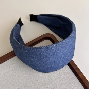 Detail of wide blue denim headband featuring yellow double stitching and vintage texture