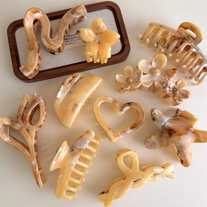 Assorted amber and cream marble hair claws in heart, flower, and star shapes