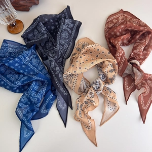Flat lay of four paisley cotton linen scarves in navy, black, beige, and brown tones