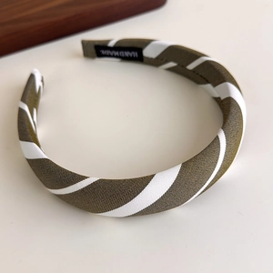 Detail of green striped fabric headband with a black Hand Made woven label inside