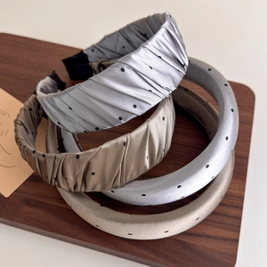 Serre-têtes en satin à pois gris et bronze posés sur un plateau en bois rustique