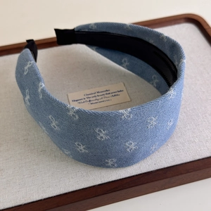 Close-up of blue denim headband with embroidered bows and non-slip inner teeth