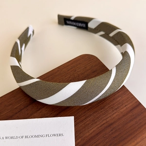 Detail of olive green striped fabric headband with a black handmade woven label