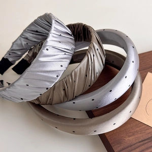 Détail de serre-têtes en satin à pois montrant le tissu brillant et le design plissé
