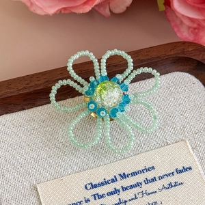 Dettaglio macro di un fiore di perline fatto a mano per scarpe con perle verdi e blu