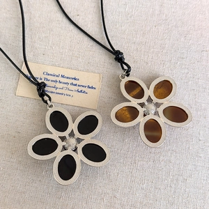 Détails des pendentifs fleurs en résine noir et marron sur supports métalliques
