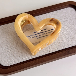Close-up of heart-shaped marble acetate hair claw clip with a strong gold metal spring
