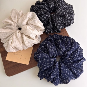 Three-piece set of large paisley print scrunchies in cream, black, and navy blue
