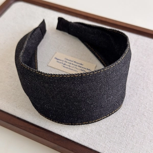 Detail showing black denim headband texture with contrast yellow topstitching and wide band