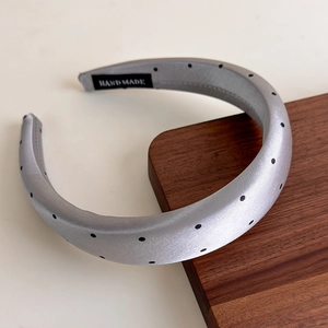 Détail d'un serre-tête fait main en satin gris à pois sur un support en bois sombre