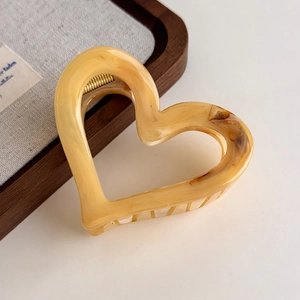 Macro detail of heart-shaped hair claw clip with yellow and brown amber marble texture