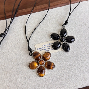 Gros plan de pendentifs fleurs en résine avec incrustations d'agate noire et œil de tigre