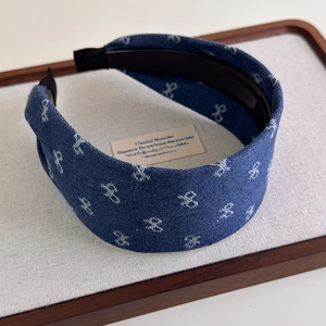 Detail of blue denim headband with white bow patterns and non-slip inner teeth structure