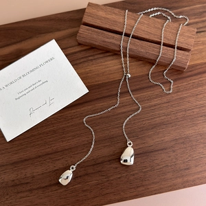 Detail of silver drop pendants with polished finish on a minimalist adjustable chain