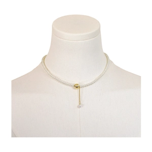 French minimalist pearl necklace with a brushed gold ball pendant on a white neck display