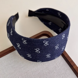 Close-up of dark blue denim headband with white bow patterns and 4cm wide non-slip design