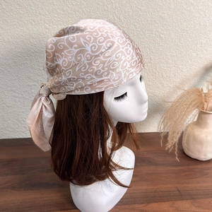 Detail of silk-like square scarf with white paisley pattern on a beige mannequin head