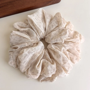 Detail of cream paisley scrunchie made of pleated chiffon fabric with floral pattern