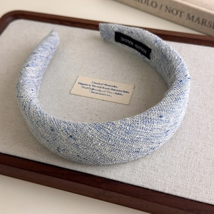 Close-up of blue tweed sponge headband showing textured fabric and handmade label