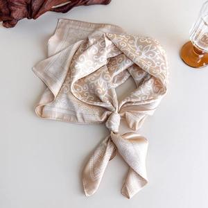 Detailed view of champagne silk square scarf with white paisley pattern print and soft drape