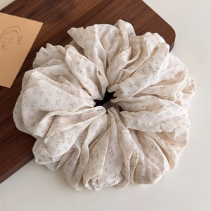 Detail view of large paisley print beige scrunchie on a rustic wooden background