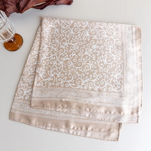 Detail of silk-feel square scarf featuring white paisley patterns on champagne gold fabric