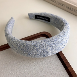 Detailed close-up of light blue tweed padded headband with a hand made woven label