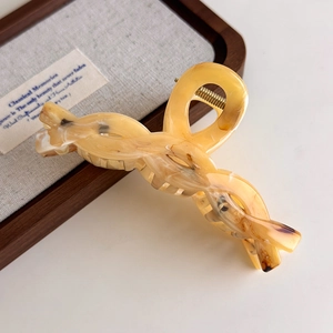 Detail of a large amber marble hair claw clip with a twisted rope design and gold metal spring