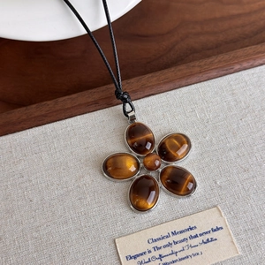 Détail du pendentif fleur en œil de tigre avec cinq pétales ovales sur cordon noir