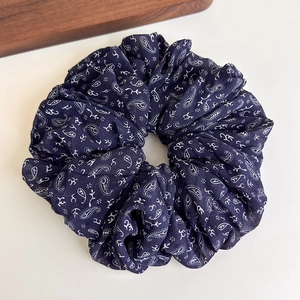 Detail of navy blue paisley print chiffon hair scrunchie with retro floral texture