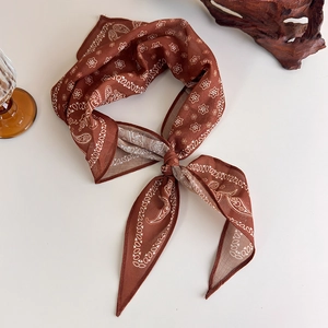 Detail of vintage dark brown paisley silk scarf with white floral patterns and light texture